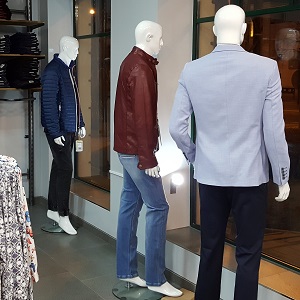 Trzy manekiny męskie stoją w oknie sklepu